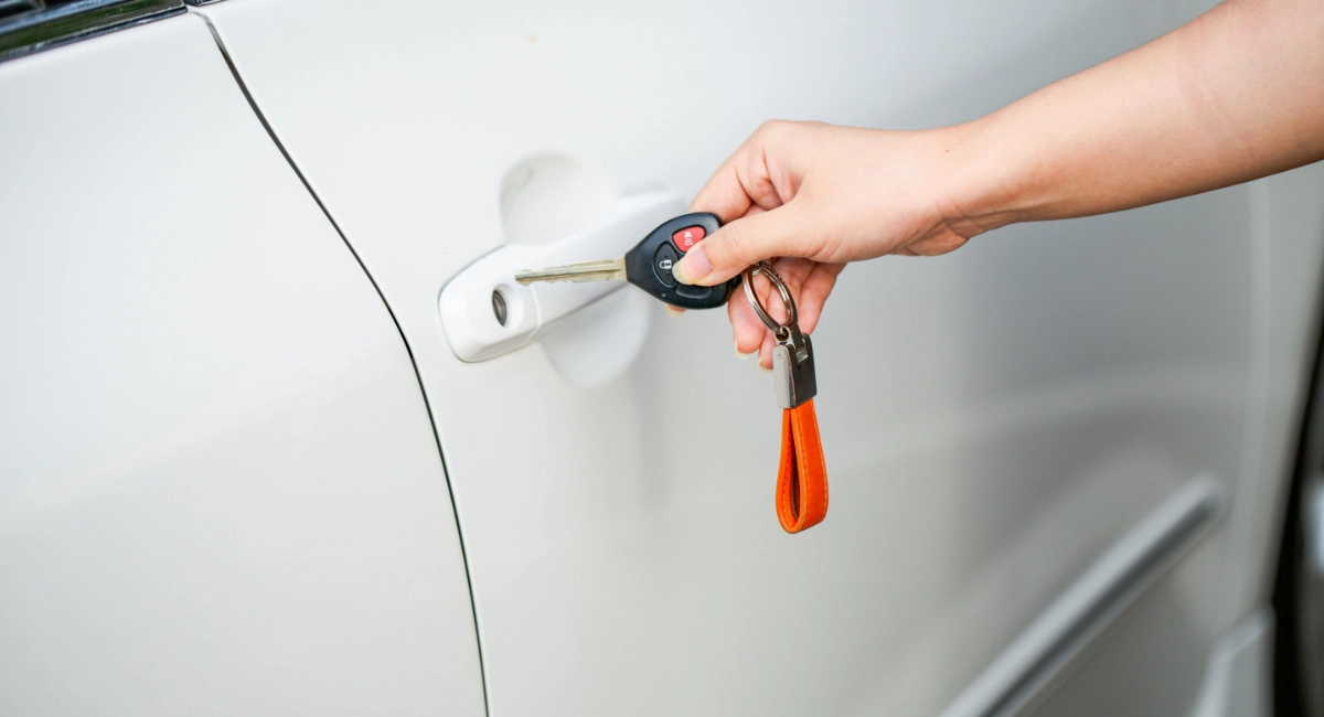 A person holding a key near a car door