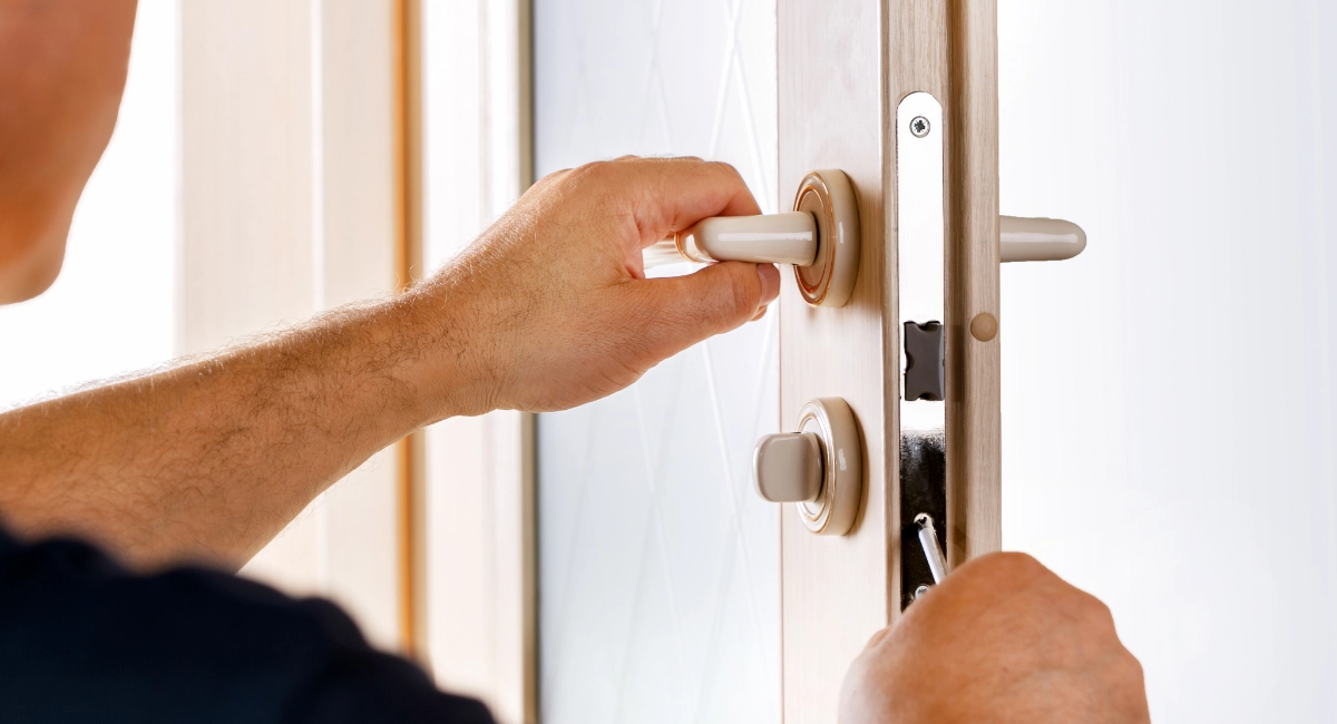 A locksmith installing a lock on a residential door.