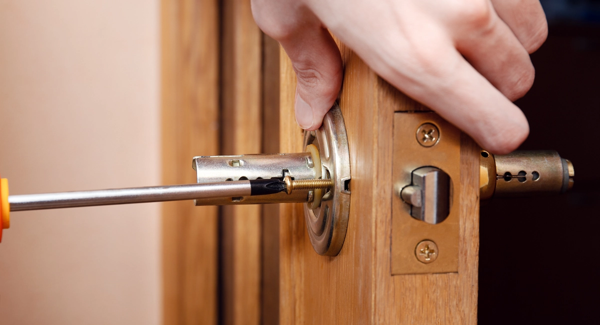 A locksmith installing a lock on a residential door.