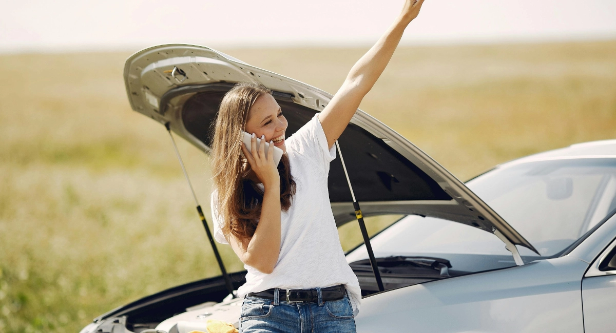 a woman talking on the phone by her car on the side of the road